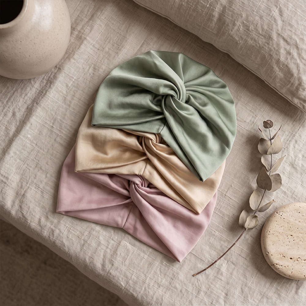 Assorted silk sleep turbans on linen bedding