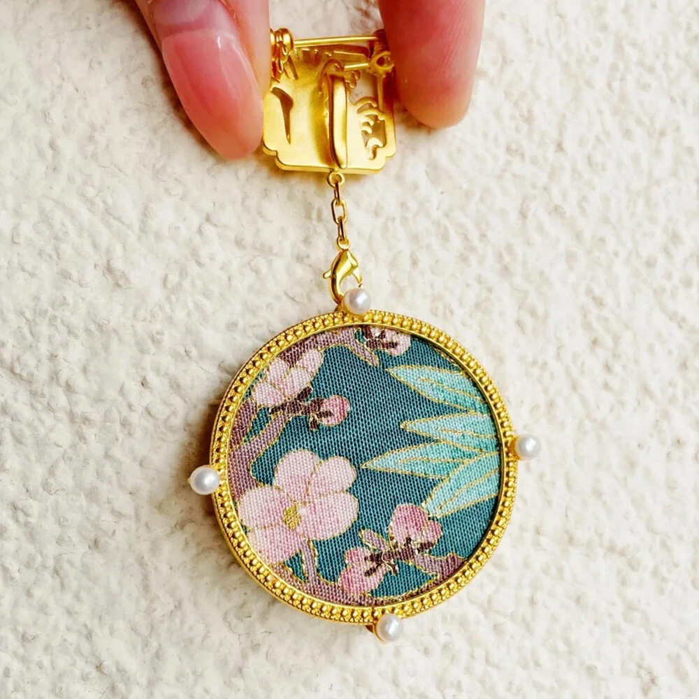 Hand holding Chinese style embroidered round pendant clip