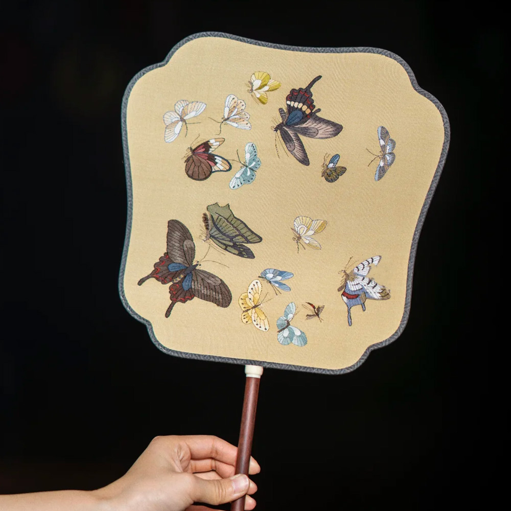 Hand holding Chinese butterfly embroidered silk paddle fan